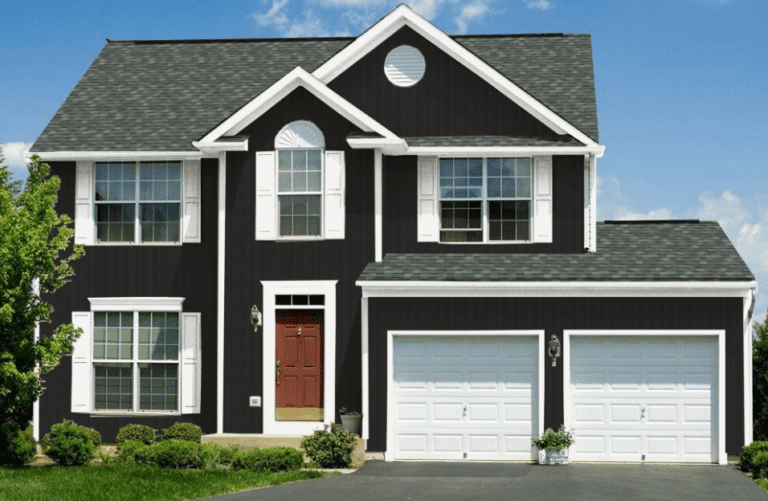 Two-story house with dark exterior, white trim, red door, two-car garage, and gray shingle roof.