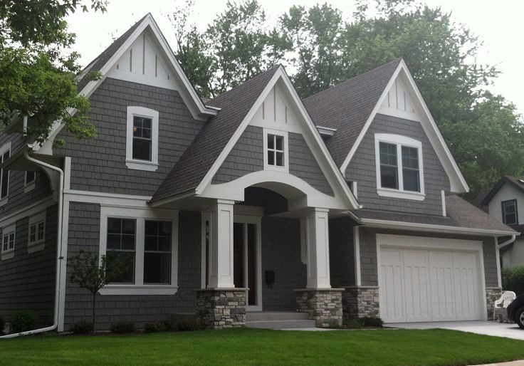 Two-story suburban house with gabled roofs, gray siding, white trim, porch, garage, and trees.
