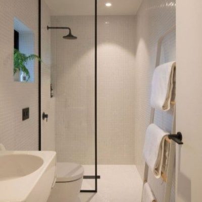 Contemporary Bathroom Design Modern bathroom with shower, glass partition, white sink, toilet, towel rack, and plant by window.